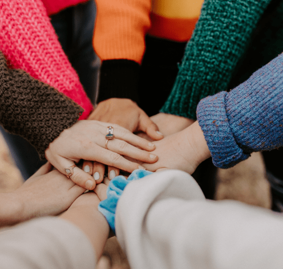 Groups with hands in circle as part of fun team building activities