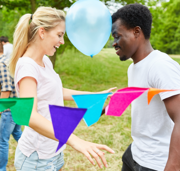 Two people playing group games with balloon between heads