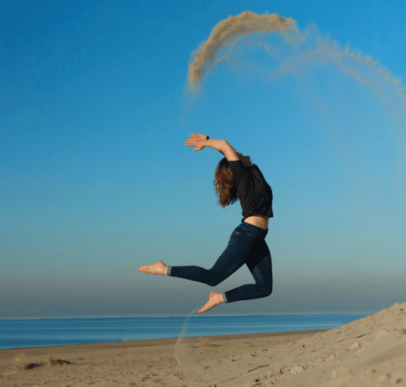 Woman jumping on beach showing ways to boost your energy